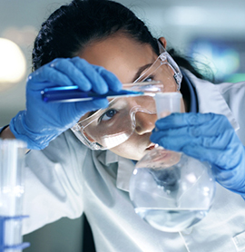 Scientist mix organic liquid in a flask in a research laboratory. Professional biochemist testing fluids and analyzing the results for her project in a medical lab, testing chemicals in a cylinder
